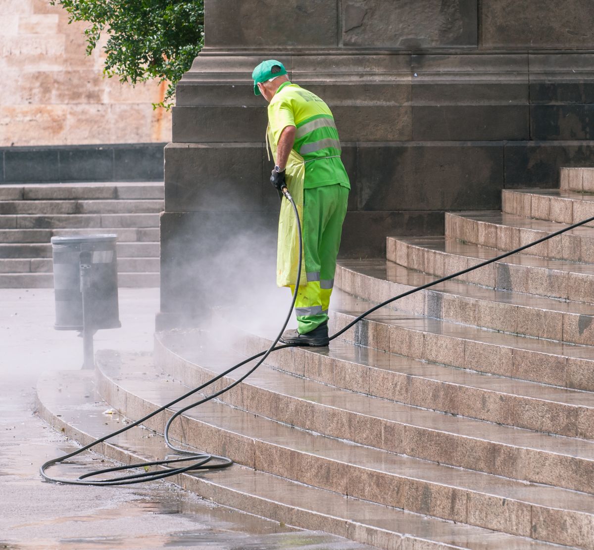 Worker using a pressure washer on outdoor stone steps