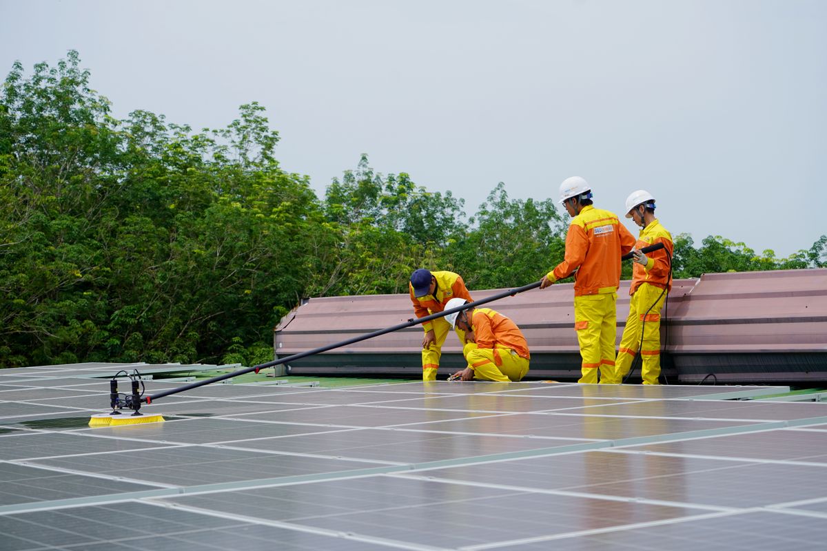Workers cleaning rooftop solar panels