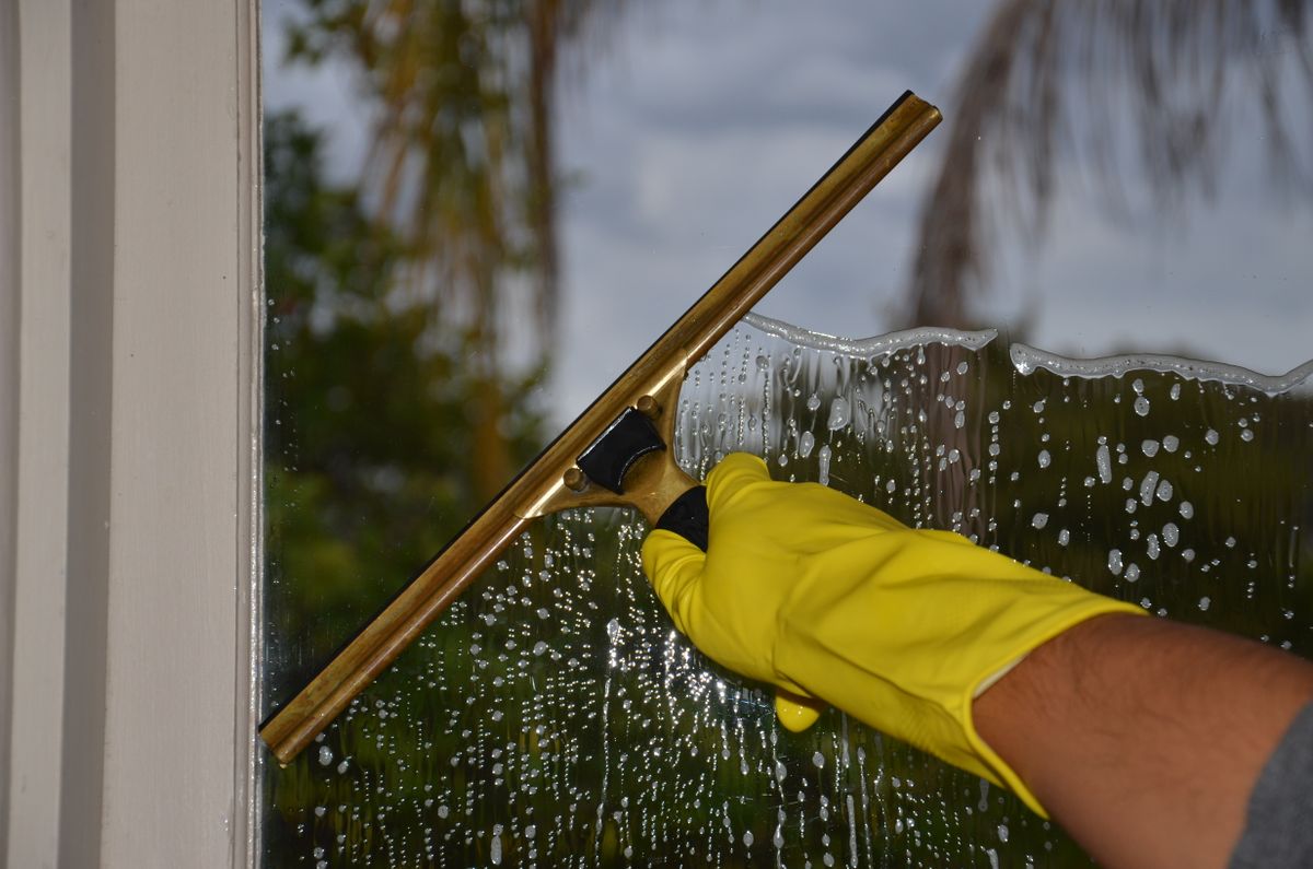 Hand cleaning a window with a squeegee